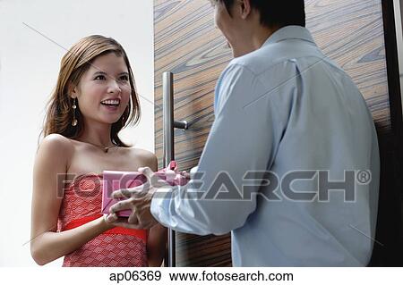 Couple standing at doorway, man giving woman a present View Large Photo Image Stock Photo - Couple standing at doorway, man giving woman a present. Fotosearch