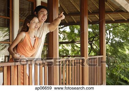 Couple standing in balcony, man pointing in the distance View Large Photo Image Stock Photo - Couple standing in balcony, man pointing in the distance. Fotosearch