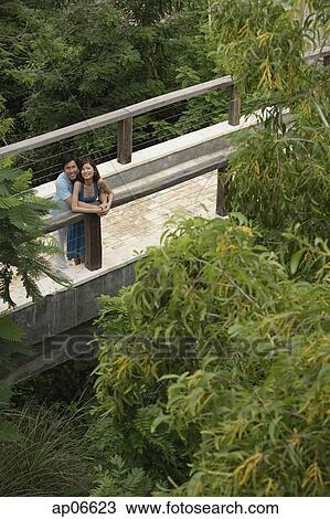 Couple standing on bridge, looking up View Large Photo Image Stock Image - Couple standing on bridge, looking up. Fotosearch