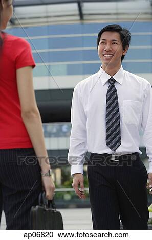 Stock Image - Male executive smiling at woman in front of him. Fotosearch