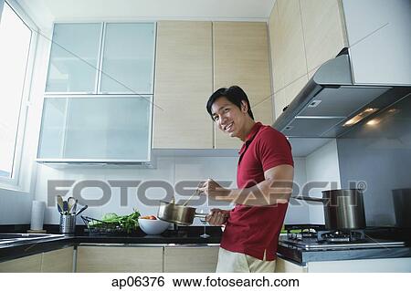 Man cooking in kitchen, smiling at camera View Large Photo Image Stock Photograph - Man cooking in kitchen, smiling at camera. Fotosearch