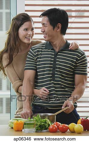 Man cooking, woman embracing him from behind View Large Photo Image Stock Photograph - Man cooking, woman embracing him from behind. Fotosearch