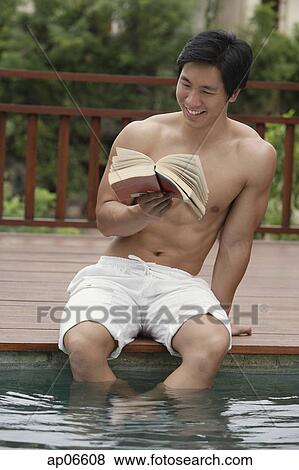 Man sitting at the edge of swimming pool, reading a book View Large Photo Image Stock Photo - Man sitting at the edge of swimming pool, reading a book. Fotosearch