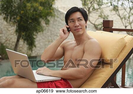 Man sitting by swimming pool, using laptop and mobile phone View Large Photo Image Stock Photo - Man sitting by swimming pool, using laptop and mobile phone. Fotosearch