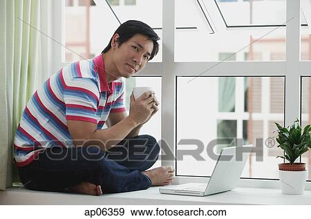 Man sitting on bay window using laptop View Large Photo Image Stock Photo - Man sitting on bay window using laptop. Fotosearch