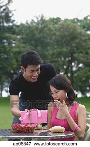 Man surprising woman with gift View Large Photo Image Stock Photo - Man surprising woman with gift. Fotosearch