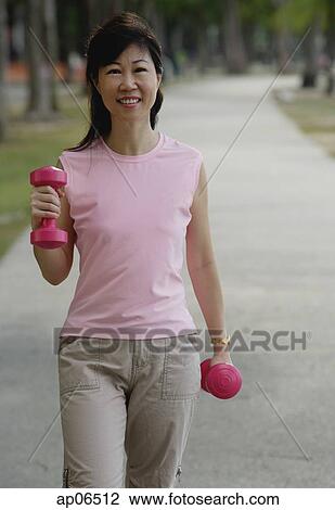 Mature woman using dumbbells in park View Large Photo Image Stock Image - Mature woman using dumbbells in park. Fotosearch