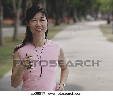 Mature woman walking in park, listening to MP3 player View Large Photo Image Stock Photo - Mature woman walking in park, listening to MP3 player. Fotosearch