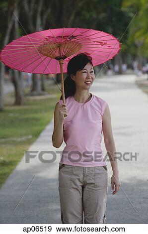 Mature woman walking in park, using pink umbrella View Large Photo Image Stock Photo - Mature woman walking in park, using pink umbrella. Fotosearch
