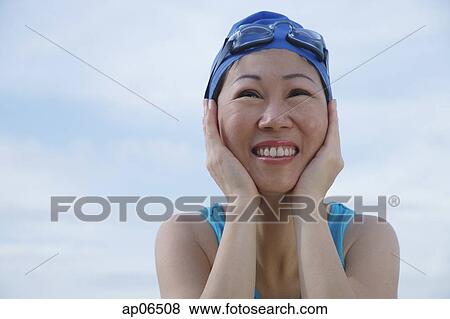 Mature woman wearing swim cap and goggles, hands on face, looking away View Large Photo Image Stock Photo - Mature woman wearing swim cap and goggles, hands on face, looking away. Fotosearch