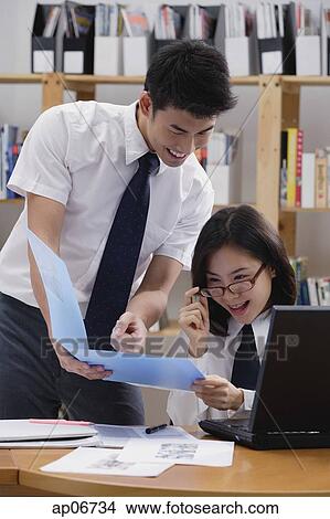 Picture - Students in library, looking at folder. Fotosearch