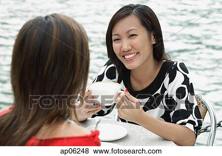 Stock Photo - Two women at sidewalk cafe having lunch. Fotosearch