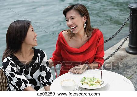 Stock Photo - Two women at sidewalk cafe having lunch, high angle view. Fotosearch