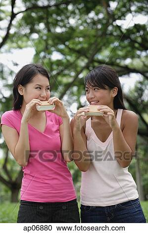 Two women eating ice cream, looking at each other View Large Photo Image Stock Image - Two women eating ice cream, looking at each other. Fotosearch