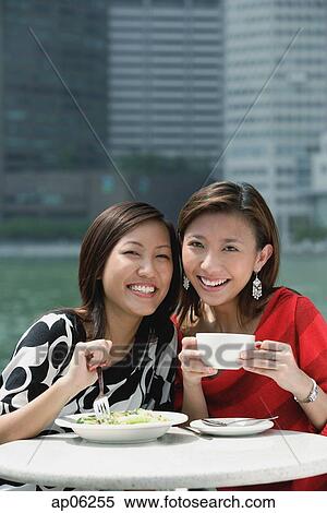 Two women having lunch, smiling at camera View Large Photo Image Stock Photography - Two women having lunch, smiling at camera. Fotosearch