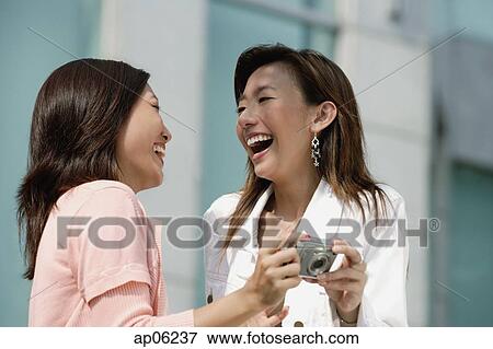 Two women laughing, holding camera View Large Photo Image Stock Photo - Two women laughing, holding camera. Fotosearch
