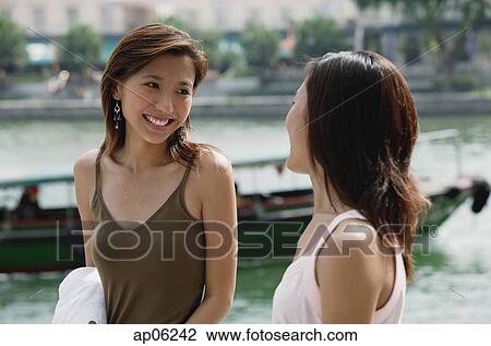 Two women smiling at each other, river behind them View Large Photo Image Stock Image - Two women smiling at each other, river behind them. Fotosearch