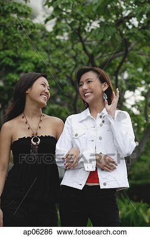 Two women walking arm in arm View Large Photo Image Stock Photograph - Two women walking arm in arm. Fotosearch
