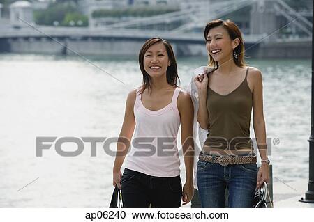 Stock Image - Two women walking side by side. Fotosearch