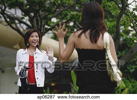 Two women walking, waving at each other View Large Photo Image Stock Photo - Two women walking, waving at each other. Fotosearch