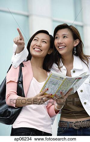 Two young women with map, looking up View Large Photo Image Picture - Two young women with map, looking up. Fotosearch