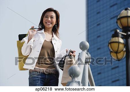 Woman carrying shopping bags, smiling View Large Photo Image Stock Photo - Woman carrying shopping bags, smiling. Fotosearch
