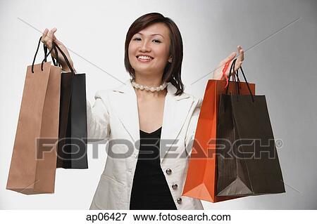 Stock Photo - Woman carrying shopping bags, smiling, portrait. Fotosearch