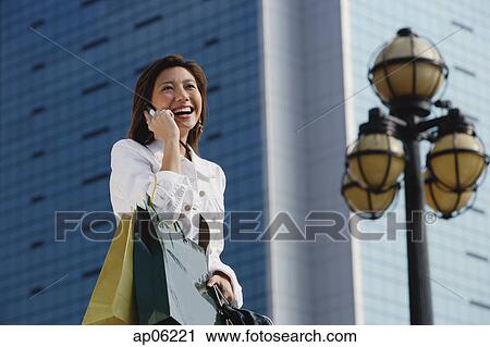 Woman carrying shopping bags, using mobile phone View Large Photo Image Stock Image - Woman carrying shopping bags, using mobile phone. Fotosearch