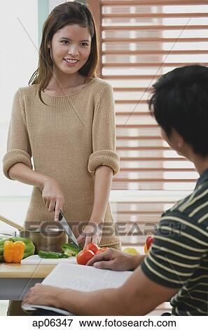 Woman chopping vegetables, looking at man in front of her View Large Photo Image Stock Photo - Woman chopping vegetables, looking at man in front of her. Fotosearch