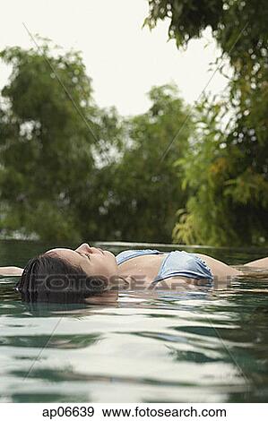 Stock Photo - Woman floating in pool. Fotosearch