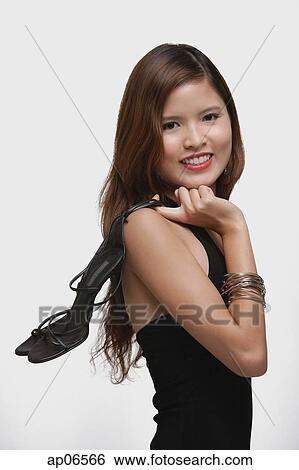 Woman holding high heeled shoes over shoulder View Large Photo Image Stock Photograph - Woman holding high heeled shoes over shoulder. Fotosearch