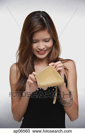Woman in black dress, looking into purse View Large Photo Image Stock Image - Woman in black dress, looking into purse. Fotosearch