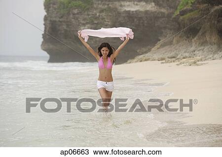 Woman in pink bikini, running along beach, holding scarf in air View Large Photo Image Stock Image - Woman in pink bikini, running along beach, holding scarf in air. Fotosearch