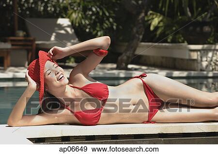 Woman in red bikini and hat, lying at the edge of swimming pool, smiling View Large Photo Image Stock Photo - Woman in red bikini and hat, lying at the edge of swimming pool, smiling. Fotosearch