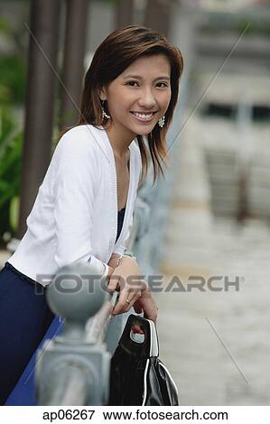 Woman leaning on railing, smiling at camera View Large Photo Image Stock Photo - Woman leaning on railing, smiling at camera. Fotosearch