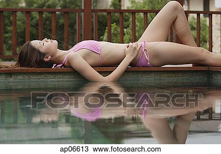 Woman lying down next to swimming pool View Large Photo Image Stock Image - Woman lying down next to swimming pool. Fotosearch