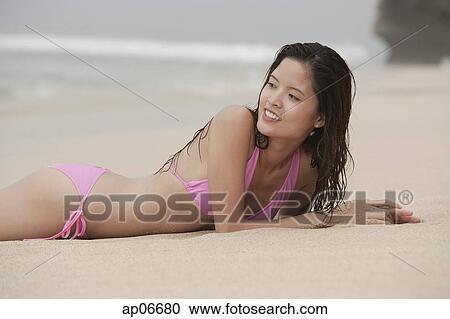 Woman lying on beach, smiling, looking over shoulder View Large Photo Image Stock Image - Woman lying on beach, smiling, looking over shoulder. Fotosearch