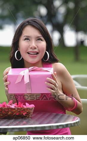 Woman sitting at outdoor cafe, holding pink gift, looking up View Large Photo Image Stock Image - Woman sitting at outdoor cafe, holding pink gift, looking up. Fotosearch