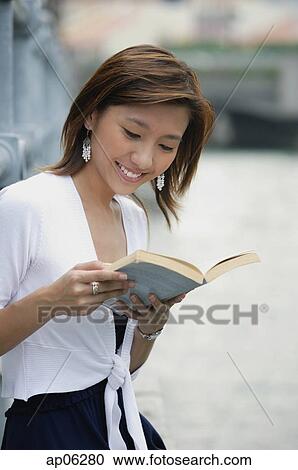Woman sitting by river, reading a book View Large Photo Image Stock Image - Woman sitting by river, reading a book. Fotosearch