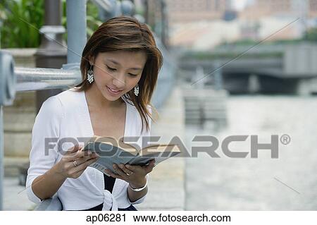Woman sitting by river, reading a book View Large Photo Image Stock Image - Woman sitting by river, reading a book. Fotosearch