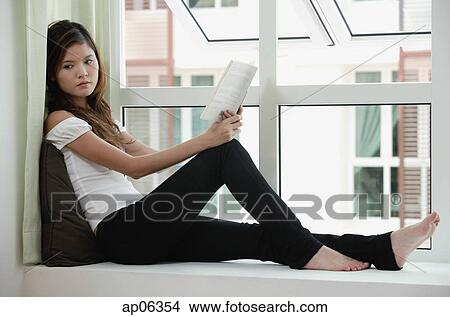 Woman sitting on bay window holding a book View Large Photo Image Picture - Woman sitting on bay window holding a book. Fotosearch