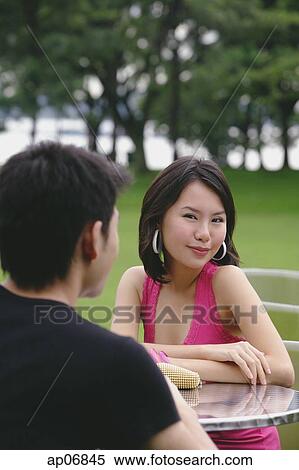 Woman smiling at camera, arms crossed, man in foreground View Large Photo Image Stock Photography - Woman smiling at camera, arms crossed, man in foreground. Fotosearch