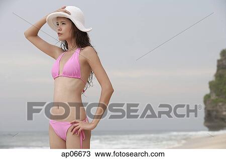 Woman standing on beach, looking away, hand on head View Large Photo Image Stock Image - Woman standing on beach, looking away, hand on head. Fotosearch