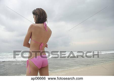 Woman standing on beach, looking away, rear view View Large Photo Image Stock Photograph - Woman standing on beach, looking away, rear view. Fotosearch