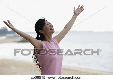 Woman standing on beach, looking up, arms outstretched View Large Photo Image Stock Photography - Woman standing on beach, looking up, arms outstretched. Fotosearch