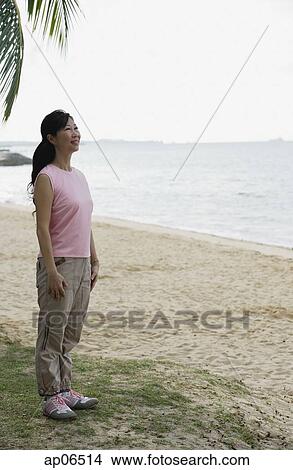 Woman standing on beach, smiling View Large Photo Image Picture - Woman standing on beach, smiling. Fotosearch