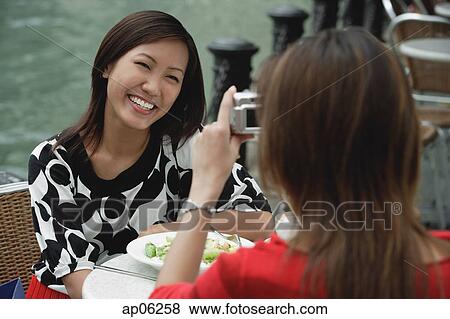 Stock Photo - Woman taking a picture of another woman. Fotosearch