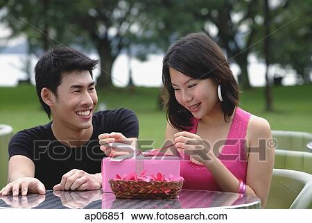 Woman unwrapping a gift, man crouching next to her, smiling View Large Photo Image Stock Image - Woman unwrapping a gift, man crouching next to her, smiling. Fotosearch