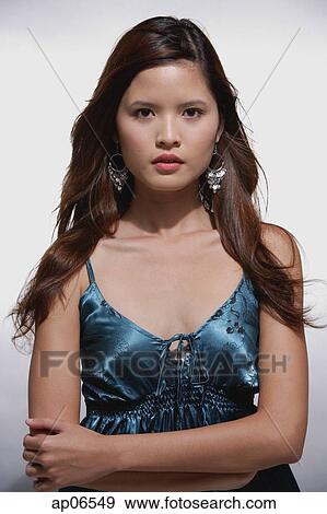 Stock Photo - Woman with long hair, looking at camera, arms crossed. Fotosearch