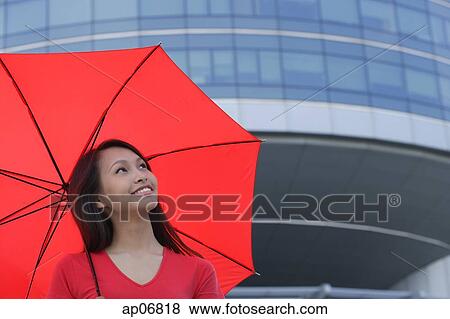 Stock Photo - Woman with red umbrella, looking up. Fotosearch